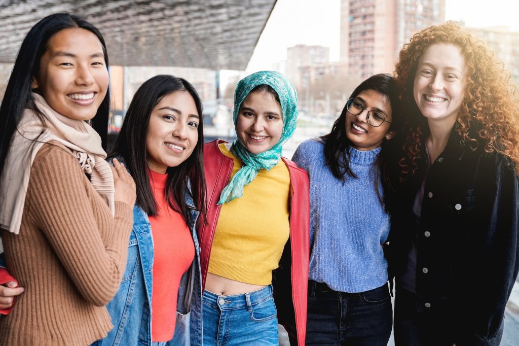 Diverse female friends having fun togehter on city street. Group of multiracial people smiling